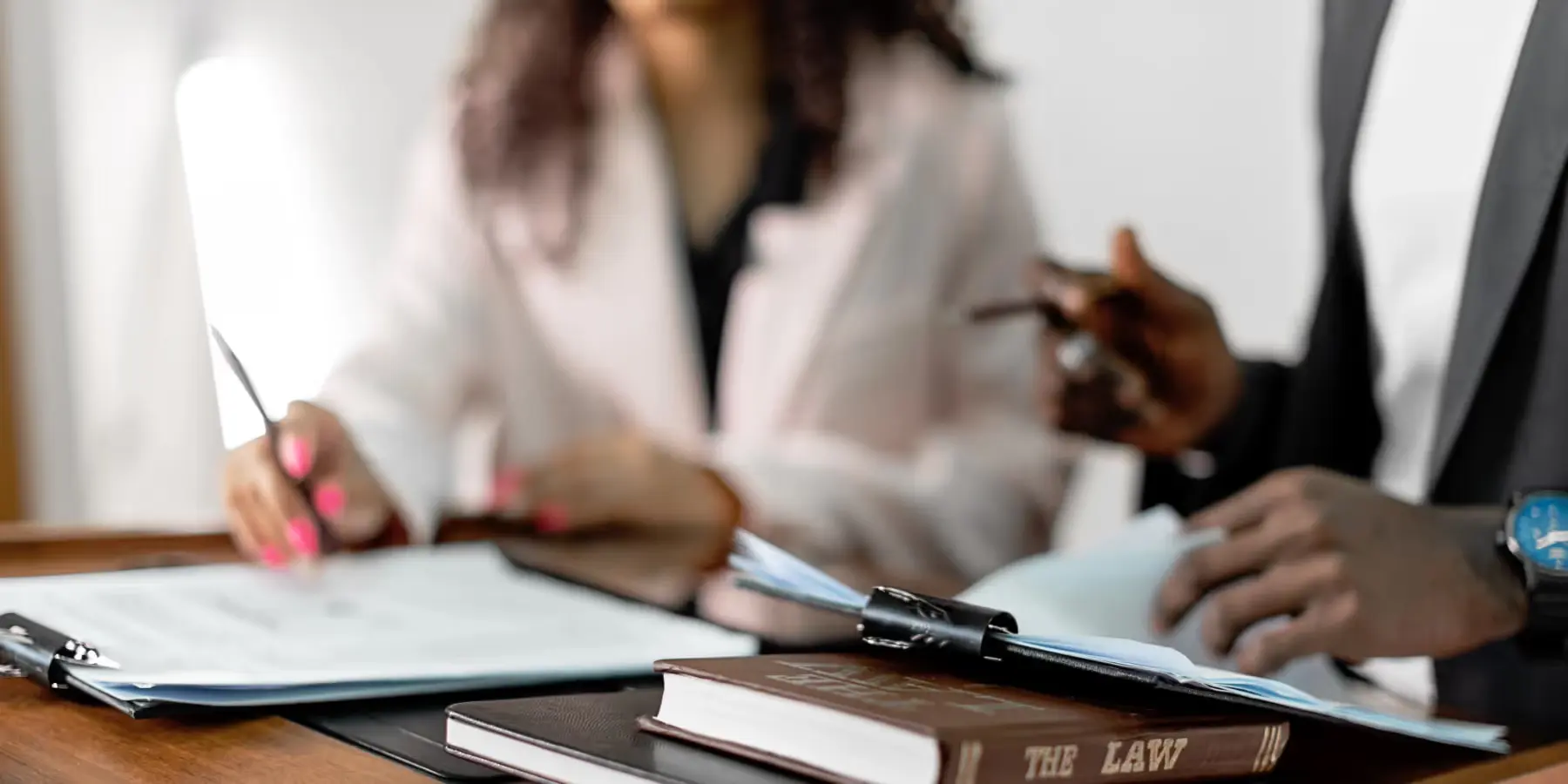 Frau und Mann bei Rechtsberatung mit Gesetzbuch auf dem Tisch