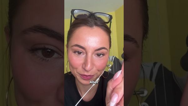 Eine Frau mit einer Brille auf dem Kopf hält einen weissen Stab mit der Aufschrift „aber“ vor ihr Gesicht.